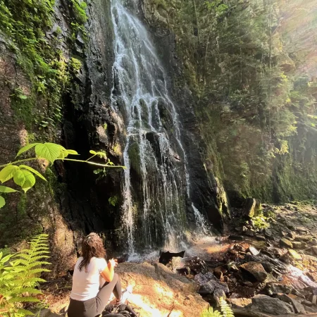 Frau sitzt vor einem Wasserfall